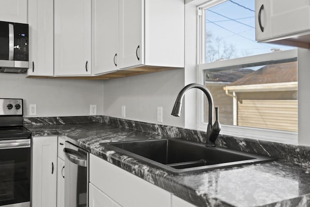 kitchen with stainless steel appliances, white cabinetry, and a sink