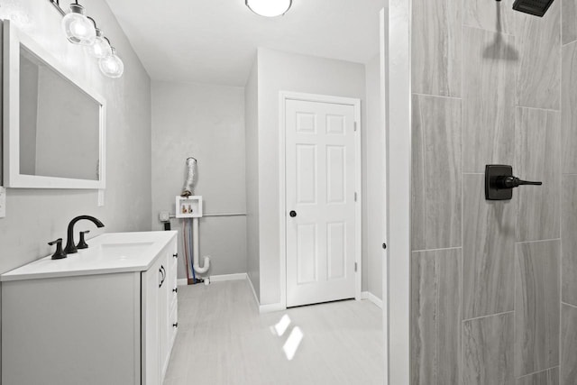 bathroom featuring a shower, vanity, and baseboards