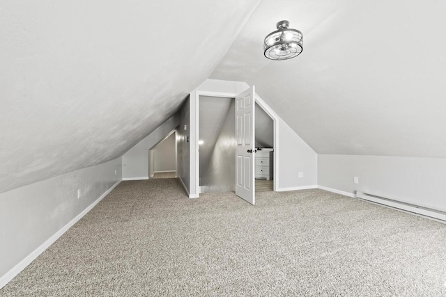 additional living space with a baseboard heating unit, baseboards, vaulted ceiling, and carpet flooring