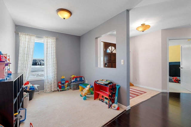 recreation room featuring baseboards and wood finished floors