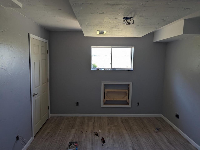 spare room with visible vents, baseboards, and wood finished floors