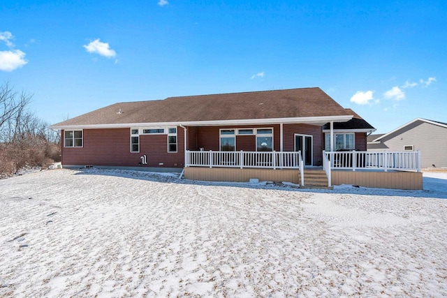 snow covered back of property featuring covered porch