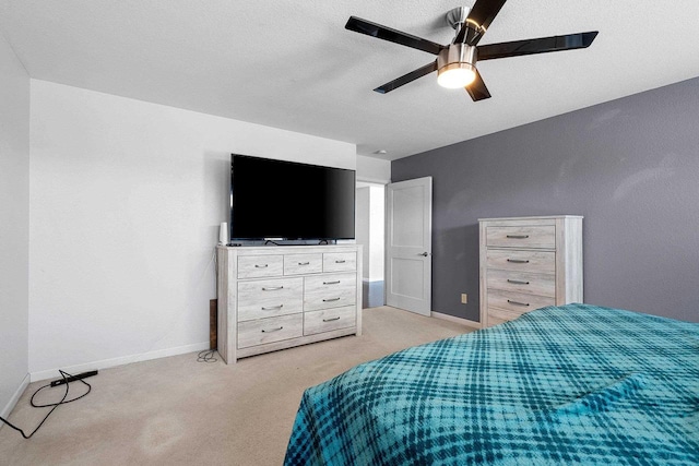 bedroom with a ceiling fan, light colored carpet, a textured ceiling, and baseboards