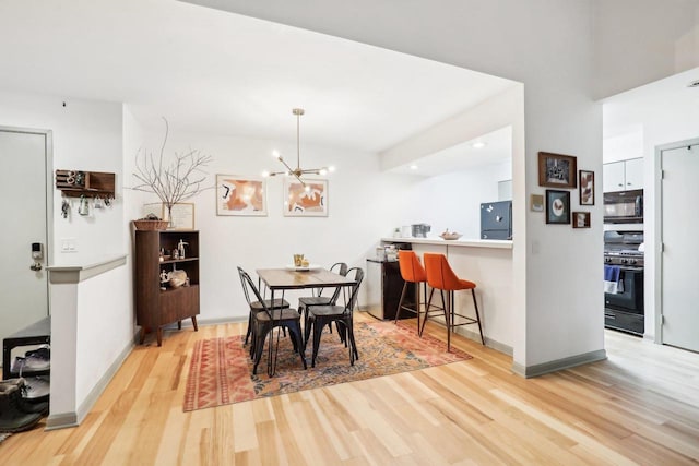 dining room with light wood-type flooring, baseboards, and a notable chandelier