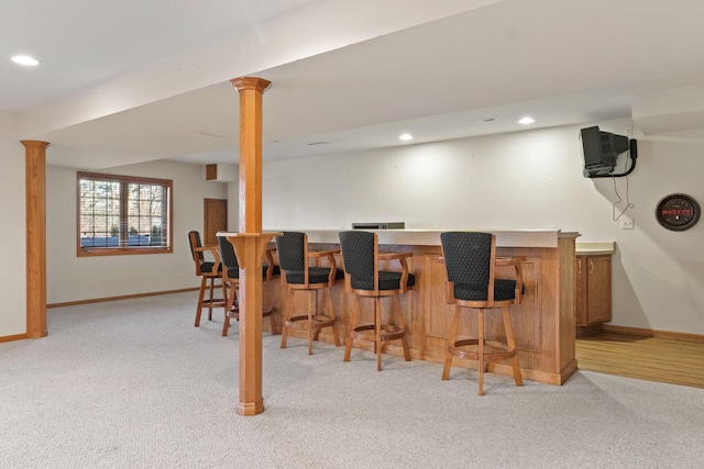 bar featuring light carpet, recessed lighting, a bar, and baseboards