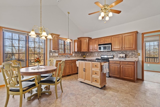 kitchen with decorative backsplash, appliances with stainless steel finishes, a center island, and high vaulted ceiling