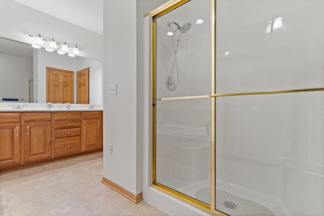 full bath with double vanity, a shower stall, baseboards, and a sink