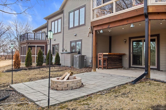 exterior space with central air condition unit, a patio, and an outdoor fire pit