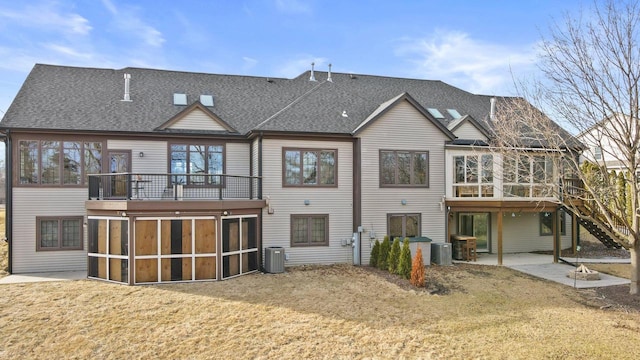 rear view of house with a patio area, central AC unit, a sunroom, and roof with shingles