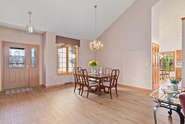 dining area with baseboards, visible vents, high vaulted ceiling, light wood-style floors, and a notable chandelier