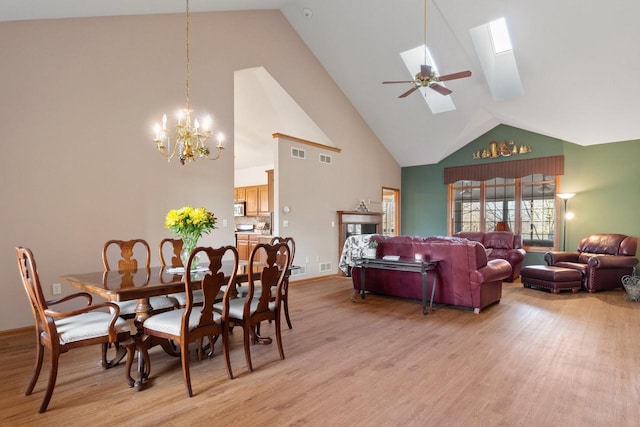 dining room with visible vents, a skylight, light wood-type flooring, and high vaulted ceiling