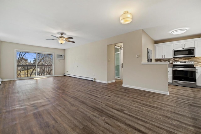 unfurnished living room with baseboard heating, a barn door, dark wood-type flooring, a ceiling fan, and baseboards