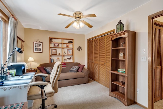 office featuring ceiling fan, baseboards, and light colored carpet