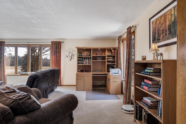 living area with built in study area, a textured ceiling, and light colored carpet