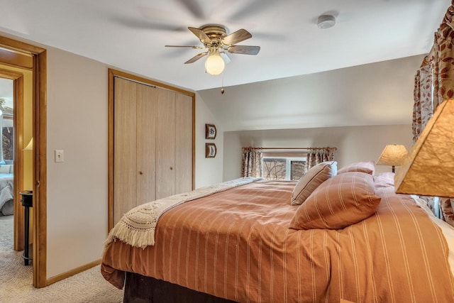 bedroom featuring light carpet, baseboards, a ceiling fan, vaulted ceiling, and a closet