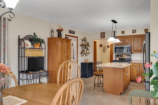 kitchen with a breakfast bar, a kitchen island, light countertops, appliances with stainless steel finishes, and brown cabinetry