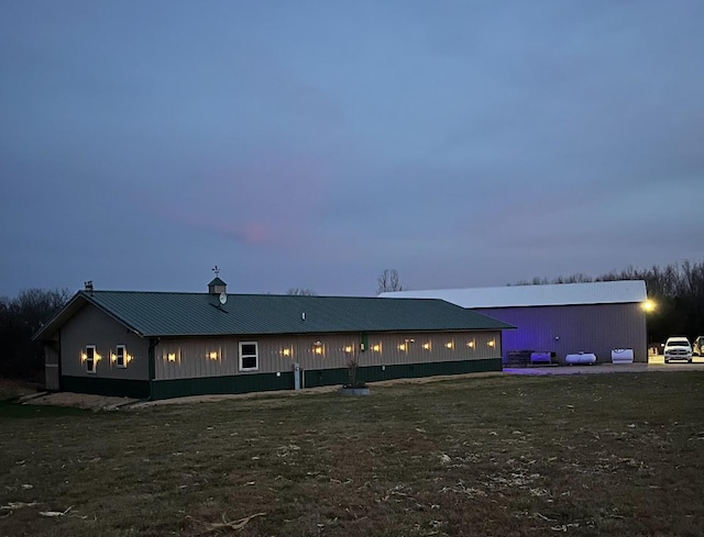 back of house with metal roof and a lawn