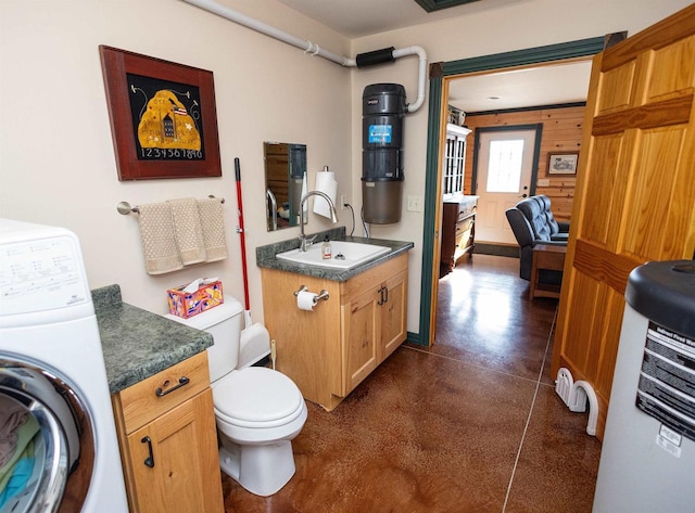 bathroom featuring concrete flooring, washer / clothes dryer, toilet, and vanity