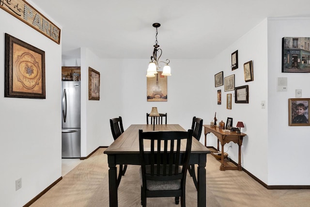 dining area featuring light carpet, baseboards, and a notable chandelier