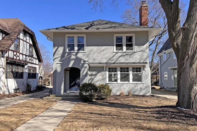 view of front of home with stucco siding, a chimney, and roof with shingles