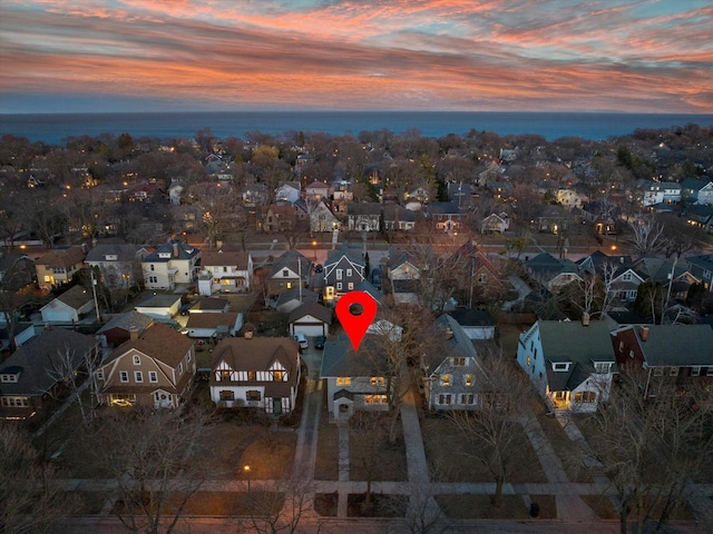 aerial view at dusk featuring a residential view and a water view