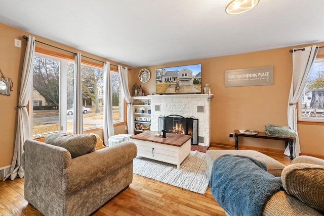 living room with a lit fireplace, baseboards, and wood finished floors