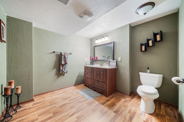 bathroom with vanity, wood finished floors, toilet, and baseboards