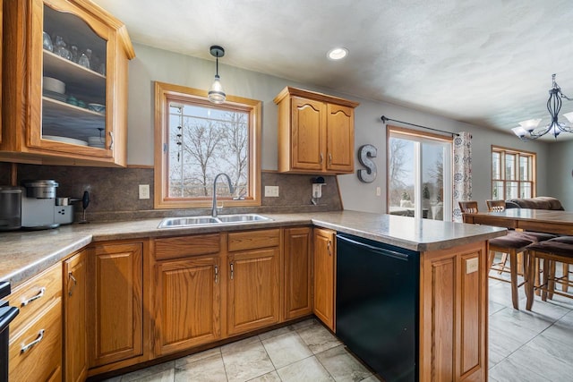 kitchen featuring a notable chandelier, a peninsula, a sink, black dishwasher, and glass insert cabinets