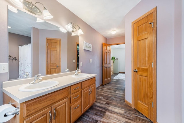 full bathroom with wood finished floors, a sink, baseboards, and double vanity