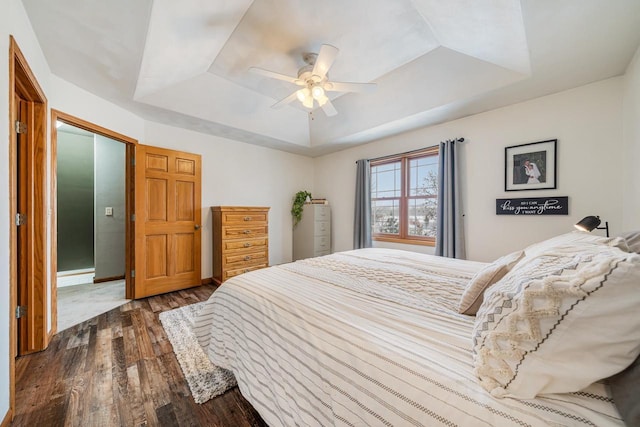 bedroom featuring a tray ceiling, dark wood finished floors, and a ceiling fan