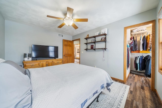 bedroom featuring wood finished floors, visible vents, baseboards, a closet, and a walk in closet