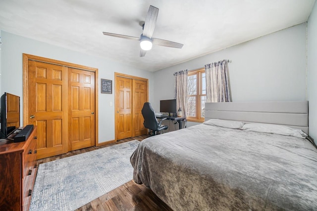 bedroom featuring multiple closets, ceiling fan, baseboards, and wood finished floors