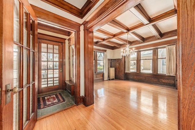 entrance foyer with coffered ceiling, radiator, hardwood / wood-style flooring, beam ceiling, and a notable chandelier