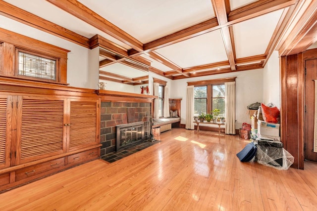 unfurnished living room with a stone fireplace, hardwood / wood-style floors, coffered ceiling, and beam ceiling