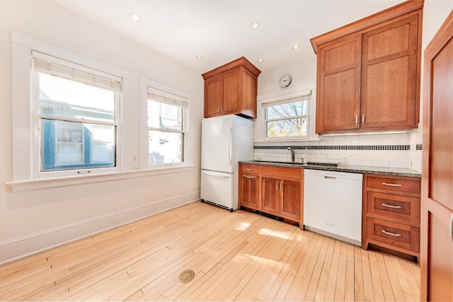 kitchen featuring white appliances, baseboards, decorative backsplash, light wood finished floors, and brown cabinetry