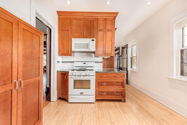 kitchen with light wood-type flooring, white appliances, brown cabinets, and backsplash