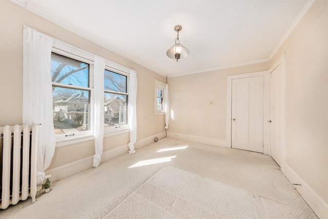 spare room featuring carpet floors, radiator heating unit, baseboards, and crown molding