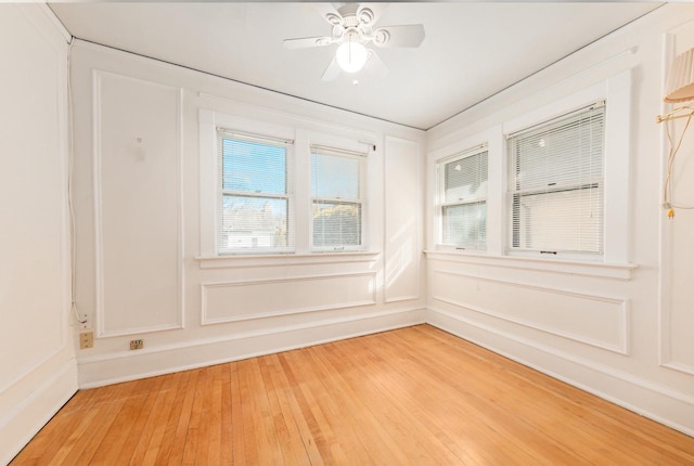 unfurnished room featuring ceiling fan, light wood finished floors, and a decorative wall