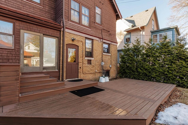 view of exterior entry featuring brick siding and a deck