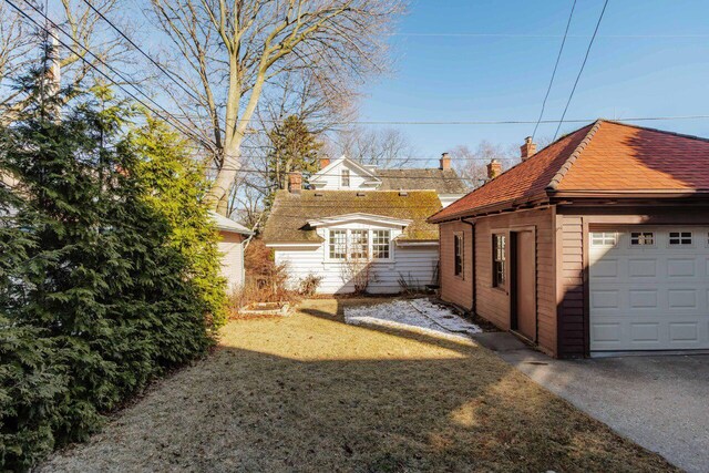 view of side of home with a garage, a lawn, and an outdoor structure