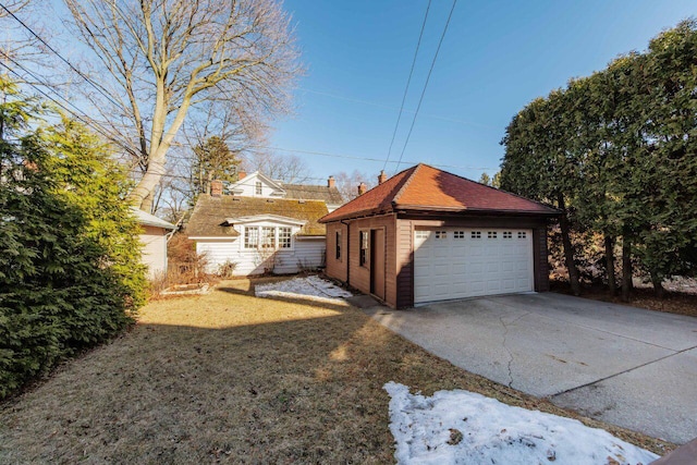 view of front facade featuring a garage, an outbuilding, a shingled roof, and a front yard