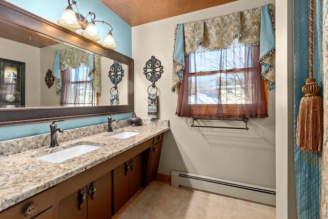 bathroom with a baseboard heating unit, double vanity, a sink, and baseboards