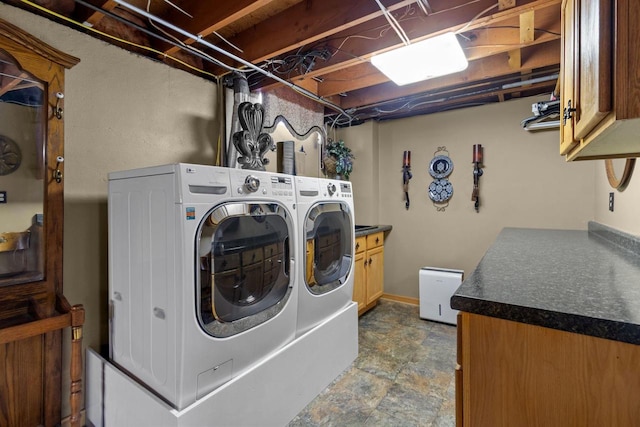 washroom featuring stone finish flooring, cabinet space, baseboards, and washing machine and clothes dryer