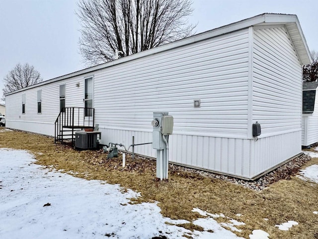 snow covered property with central air condition unit