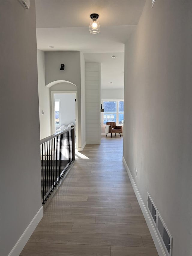 hallway featuring wood finished floors, visible vents, and baseboards