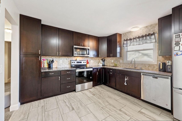 kitchen with dark brown cabinetry, backsplash, appliances with stainless steel finishes, and a sink