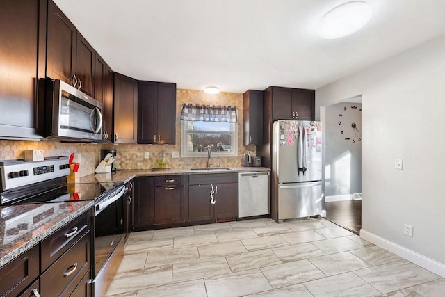 kitchen with dark brown cabinets, backsplash, appliances with stainless steel finishes, and a sink