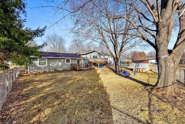 exterior space featuring fence, a lawn, and a wooden deck