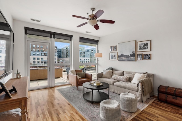 living room with light wood-type flooring, visible vents, and a city view