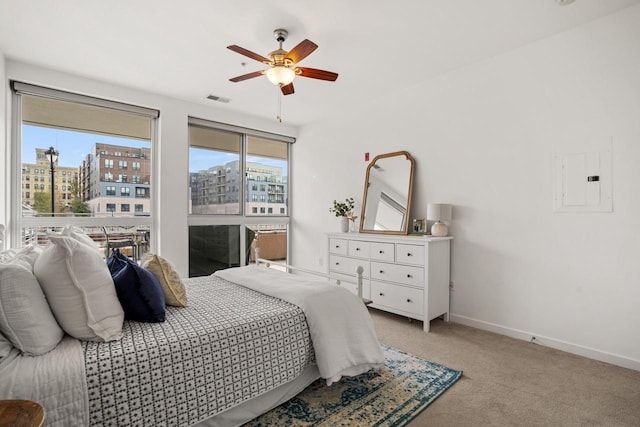 bedroom with a view of city, baseboards, light colored carpet, and multiple windows